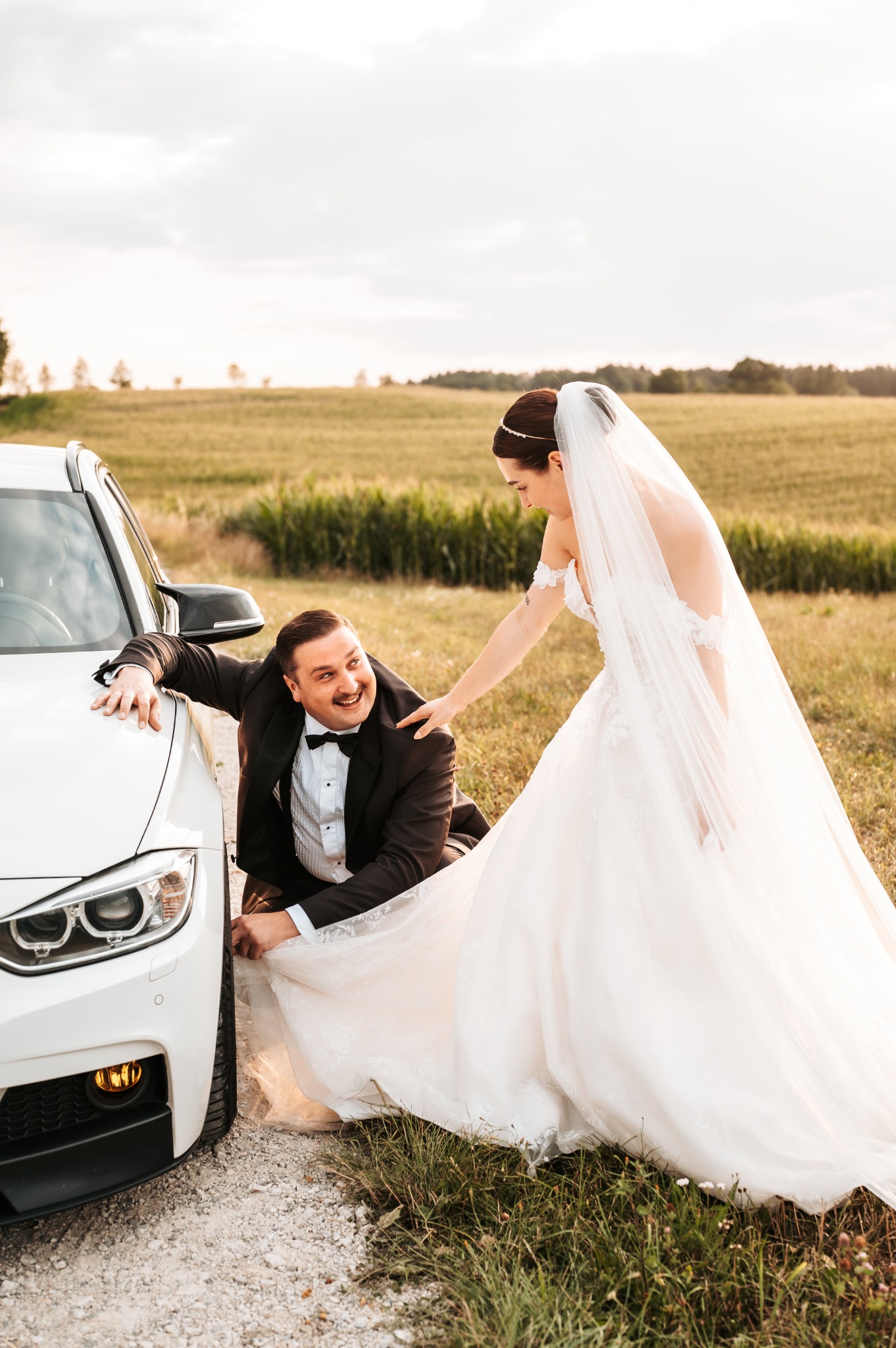 Nós dois em trajes de casamento ao lado do nosso Touring branco.